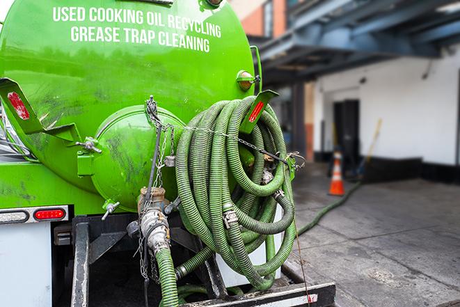 a technician pumping a grease trap in a commercial building in Francis Creek